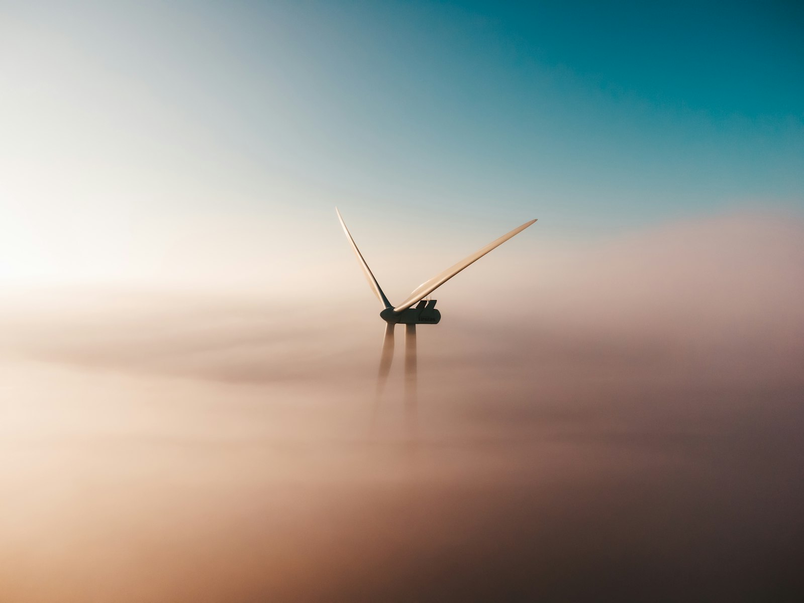 A wind turbine rising out of fog at sunrise — the fleet SUNWARD listens to